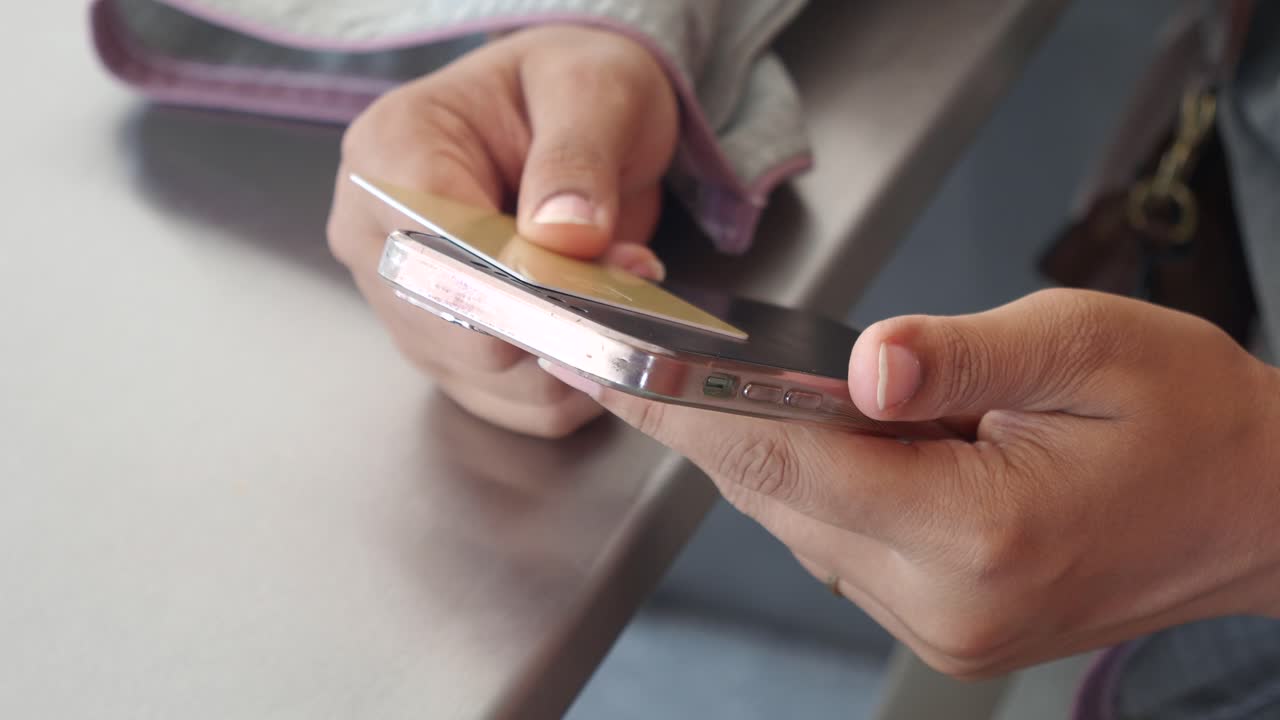 Person using a smartphone and credit card for mobile payment.