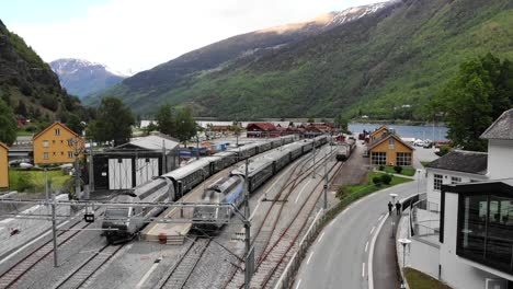 aerial: train by a river entering flåm station