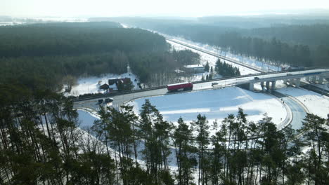 aerial view of countryside vehicles running on road bridge over railway during winter season in rakowice, kraków, poland - aerial drone shot