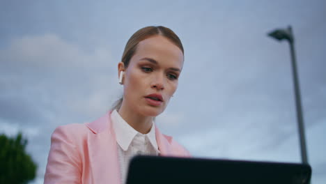 online speaker talking laptop camera sitting outdoors in earphones close up.