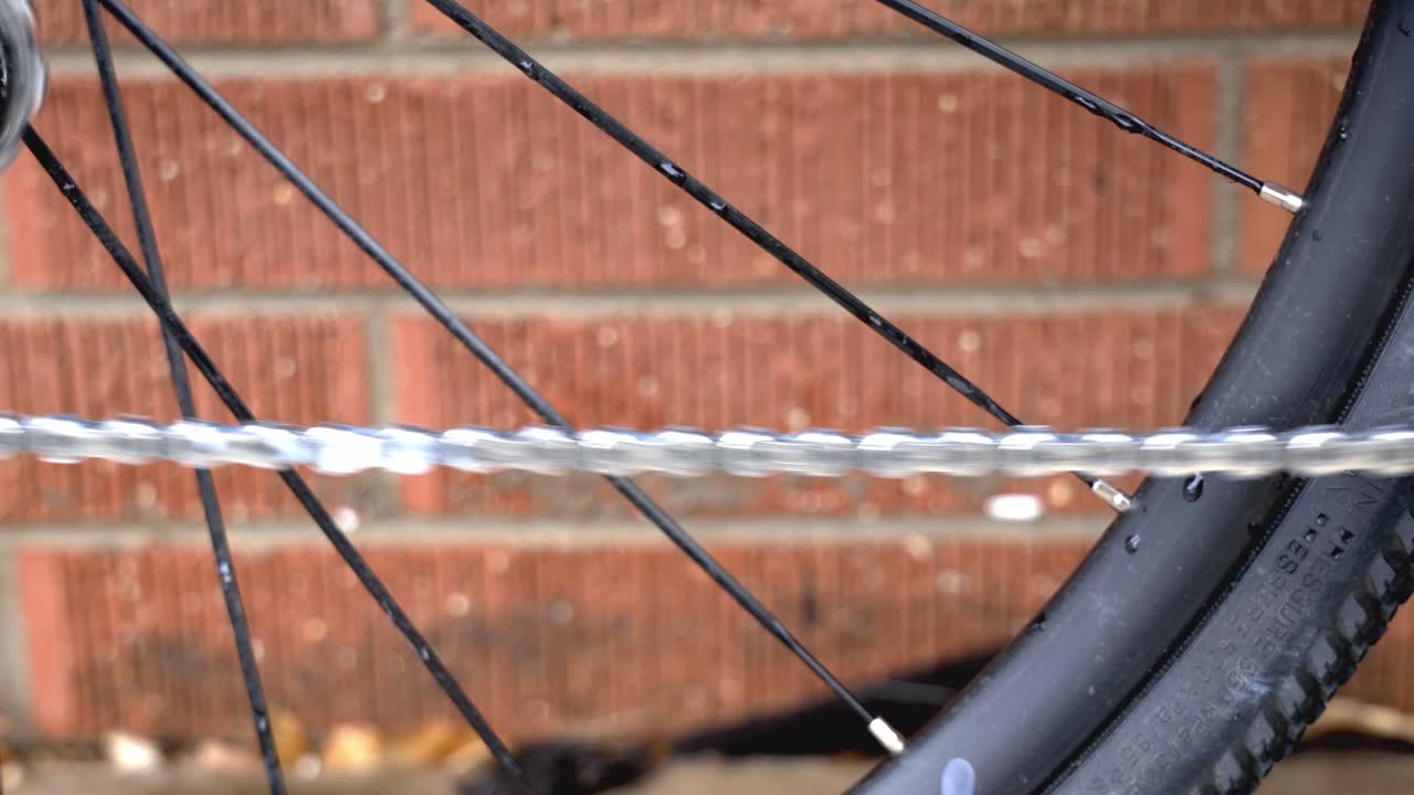 일상적인 유지 관리의 일환으로 윤활유를 사용하여 움직이는 자전거 체인을 닫습니다.