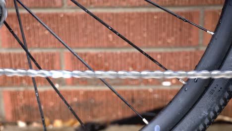 primer plano de una cadena de bicicleta en movimiento con lubricante como parte del mantenimiento de rutina