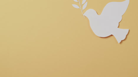 close up of white dove with leaf and copy space on yellow background