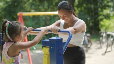 pregnant mother and daughter exercising at outdoor gym