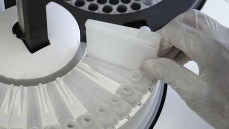 técnico de laboratorio con guante quita la botella de reactivo en el analizador de química