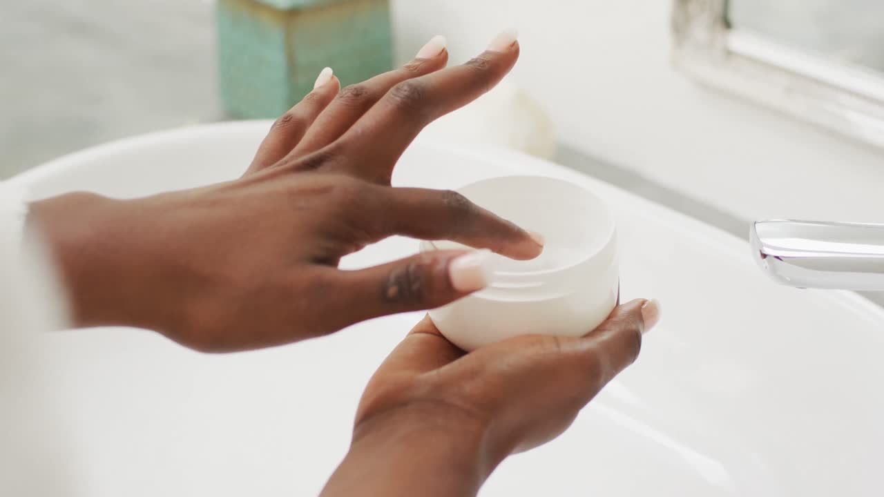 vídeo de mãos de mulher afro-americana segurando creme facial
