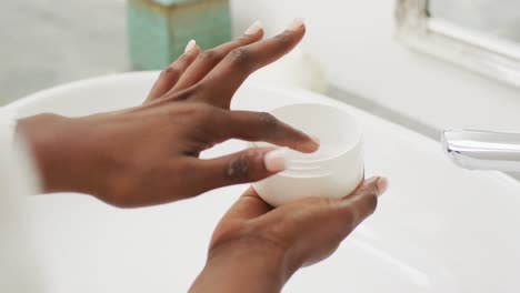 video of hands of african american woman holding face cream