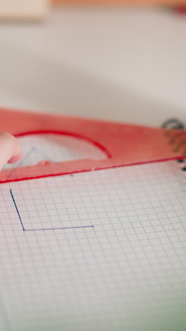 little student draws triangular shape with ruler and pen on copybook page at desk closeup. schoolgirl studies figures doing homework at home