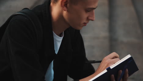 joven estudiante escribiendo notas al aire libre.