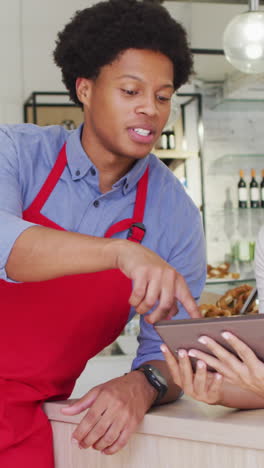 video of happy diverse female owner and male waiter working with tabletat cafe shop