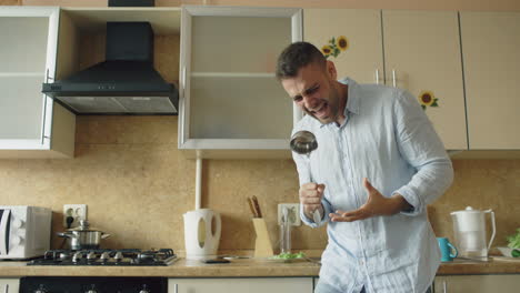 man singing in kitchen with a spoon