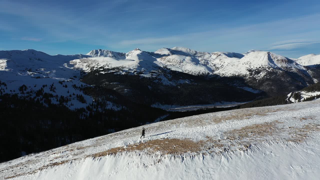 Vista aerea di una persona che cammina in salita in uno splendido paesaggio invernale innevato di una catena montuosa rocciosa, Nord America.