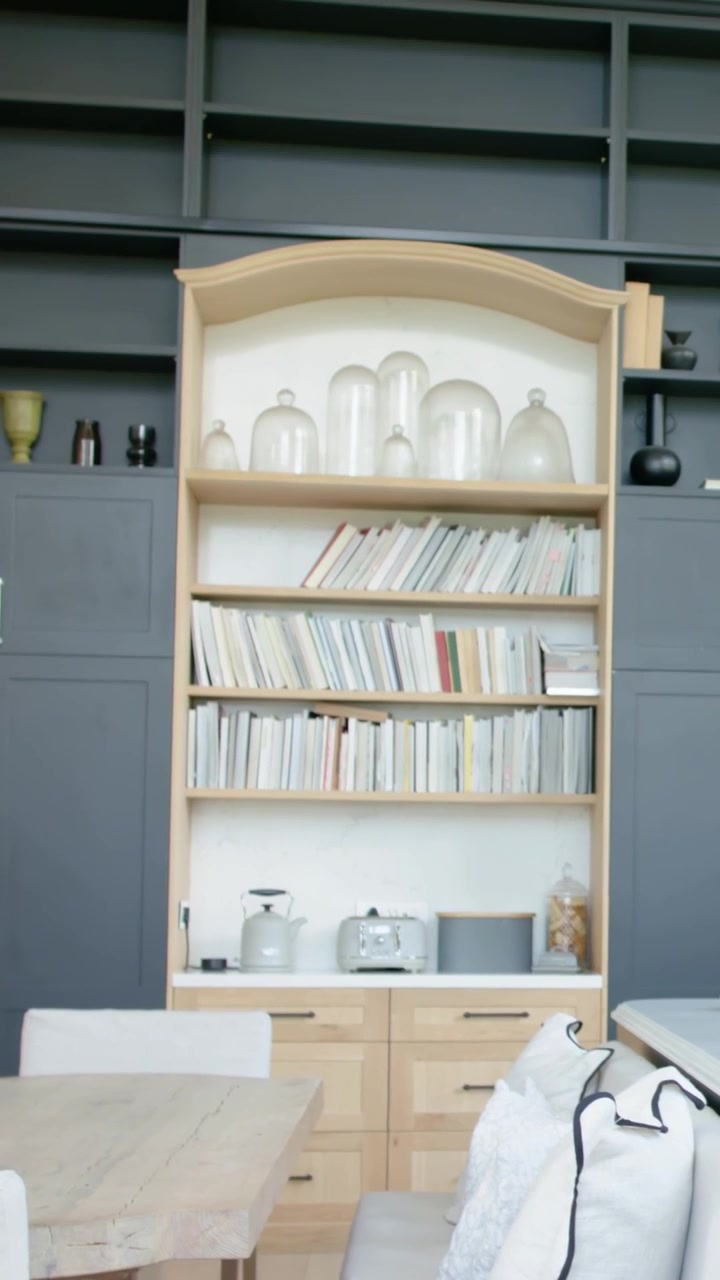 Vertikales Video: Schwenkende Kamera zentriert hohes Bücherregal im Essbereich, enthüllt Cloches, Bücher