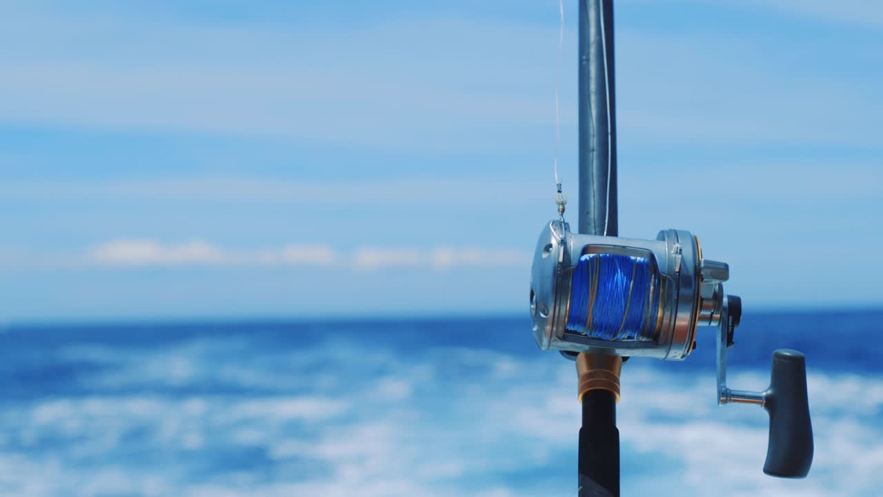 Close up on blue fishing reel with Caribbean Sea background