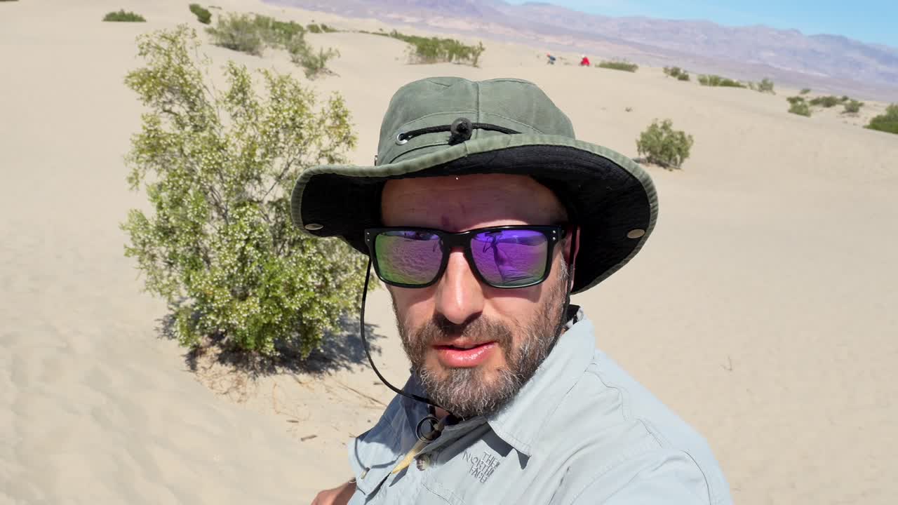 Man in Hat and Sunglasses Talking in Desert Landscape