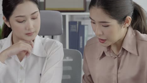 두 젊은 열정적인 사업가 여성이 사무실 작업 공간에서 함께 일하고 있습니다.