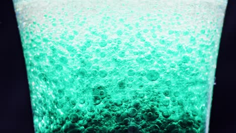 macro shot of sparkling blue bubbles floating around in a glass with bright background