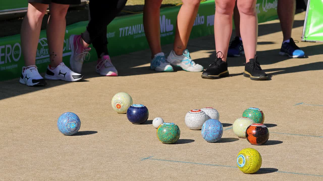 I giocatori si cimentano in una partita di bocce su prato in una giornata di sole, mostrando abilità e precisione sul tappeto erboso.