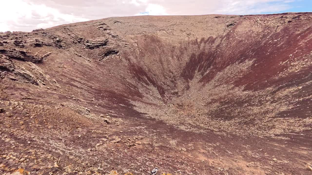 Breathtaking View of a Deep Volcanic Crater from the Summit Rim in Fuerteventura Spain During Daytime with Arid Landscape