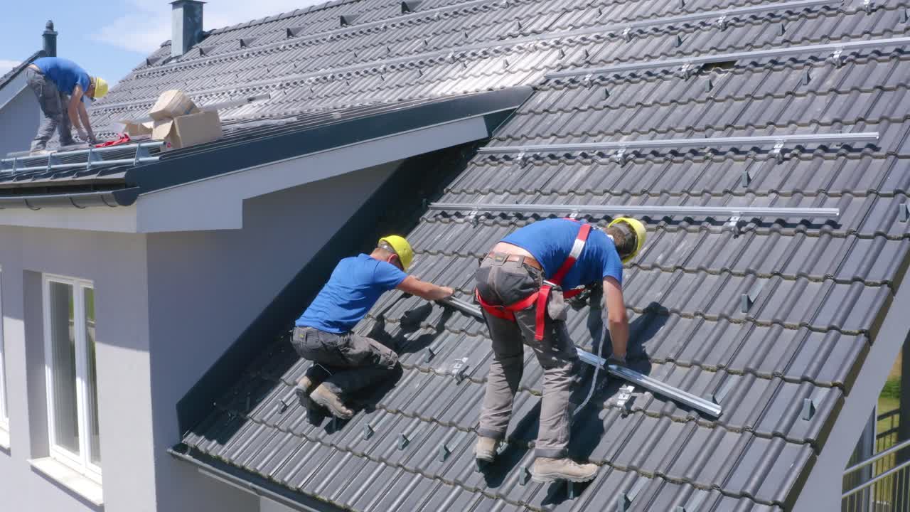 Uomini che installano i binari dei pannelli solari sul tetto. Concetto ecologico