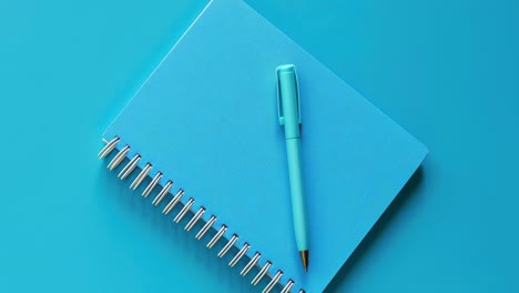 blue spiral notebook and pen on blue background