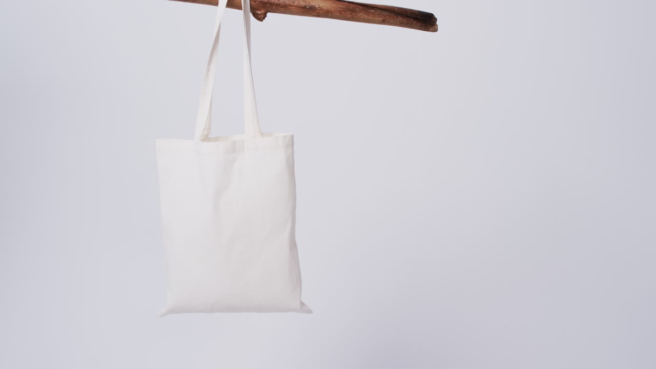 Video di borsa di tela bianca appesa a un ramo con spazio per il testo su sfondo bianco