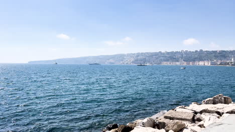 vista del mar y la costa desde una orilla rocosa, barcos en la distancia - sorento, italia