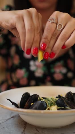 woman squeezing lemon over mussels and pasta