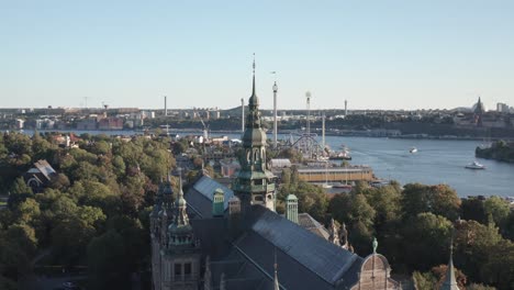 Aerial-view-of-Nordiska-Museet-with-Gröna-Lund-in-background-on-sunny-evening-on-Djurgården-in-Stockholm,-Sweden