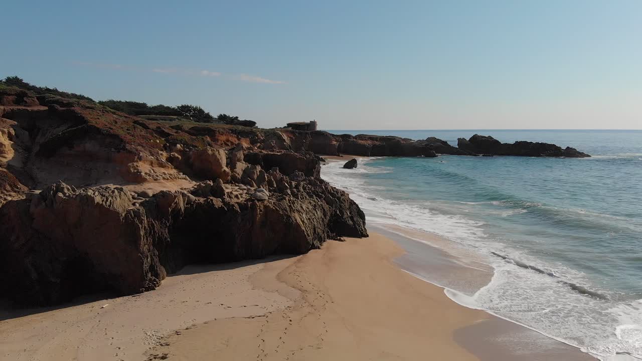 Praia rochosa na Califórnia com ondas quebrando na areia