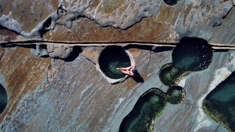 Figure-8-Pool,-Australia,-Drone-Ascending-Shot,-Girl-Sitting-at-Edge-of-Pool