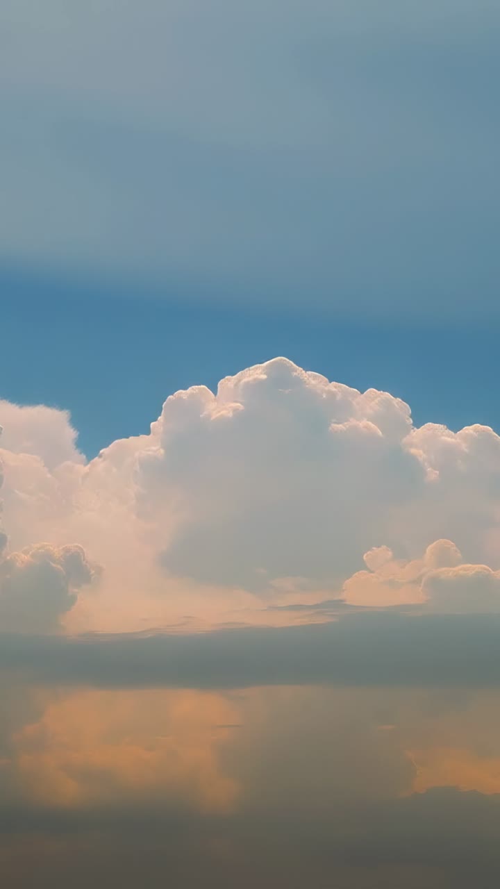 Vertical video: Cumulus clouds turning pinkish orange with sunset unfolding in open sky