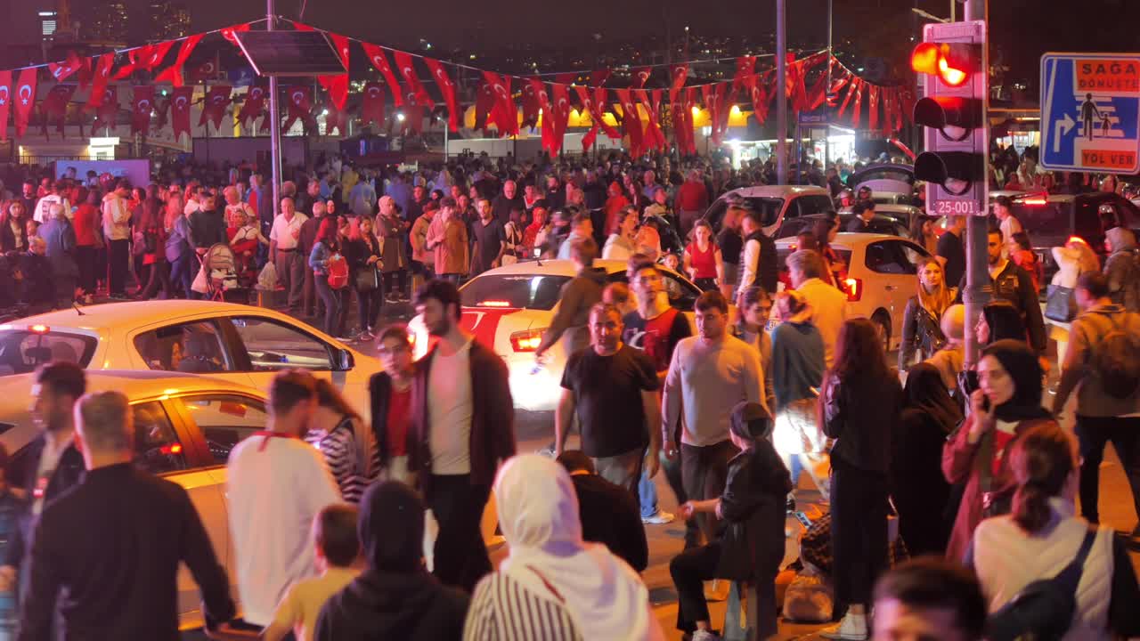 una gran multitud de personas se reúne en una calle de la ciudad por la noche