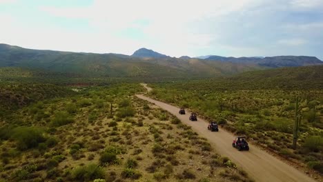 aerial drone shot of four utv's driving through the arizona desert on a cloudy day