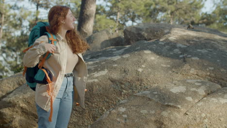 red haired woman backpacker climbing mountain hill while hiking on a sunny autumn day in the forest