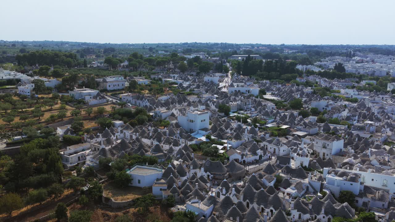 Alberobello, famous trulli village, UNESCO World Heritage site in Puglia, Italy, unique conical stone roofs and whitewashed houses. Aerial backward tilt-up reveal