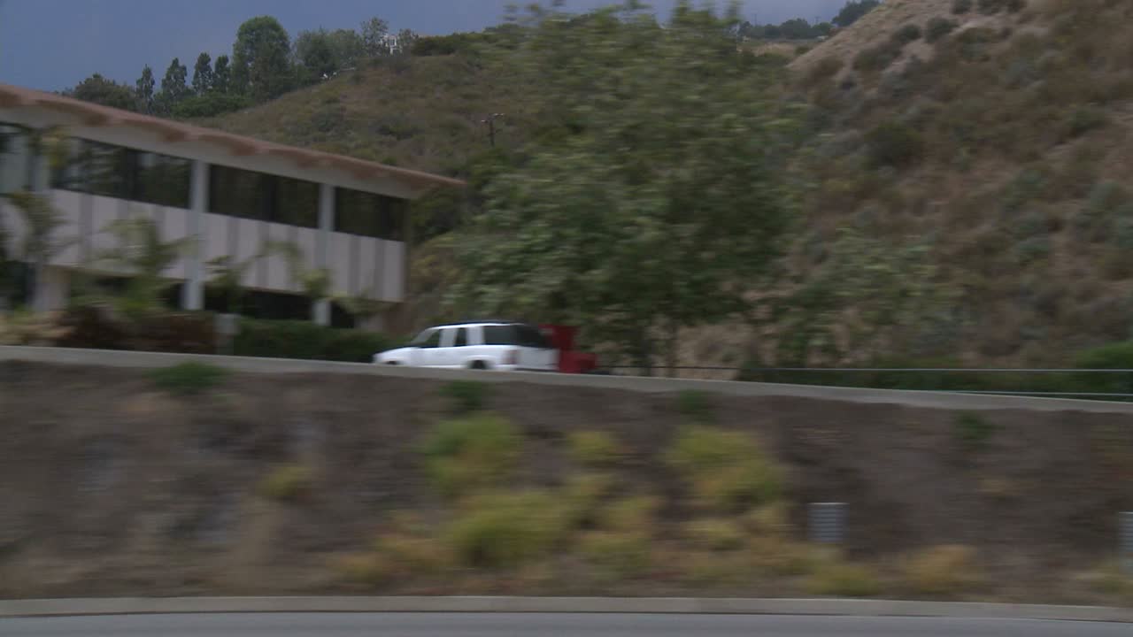 사이드 윈도우 2를 통해 보이는 태평양 연안 고속도로를 따라 자동차가 이동합니다.