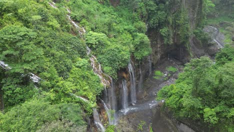 aerial descends into deep misty lush waterfall canyon on java, idn