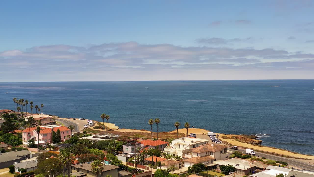 Drone che vola sopra case e palme a Ocean Beach San Diego durante il tramonto dirigendosi verso l'oceano e la costa