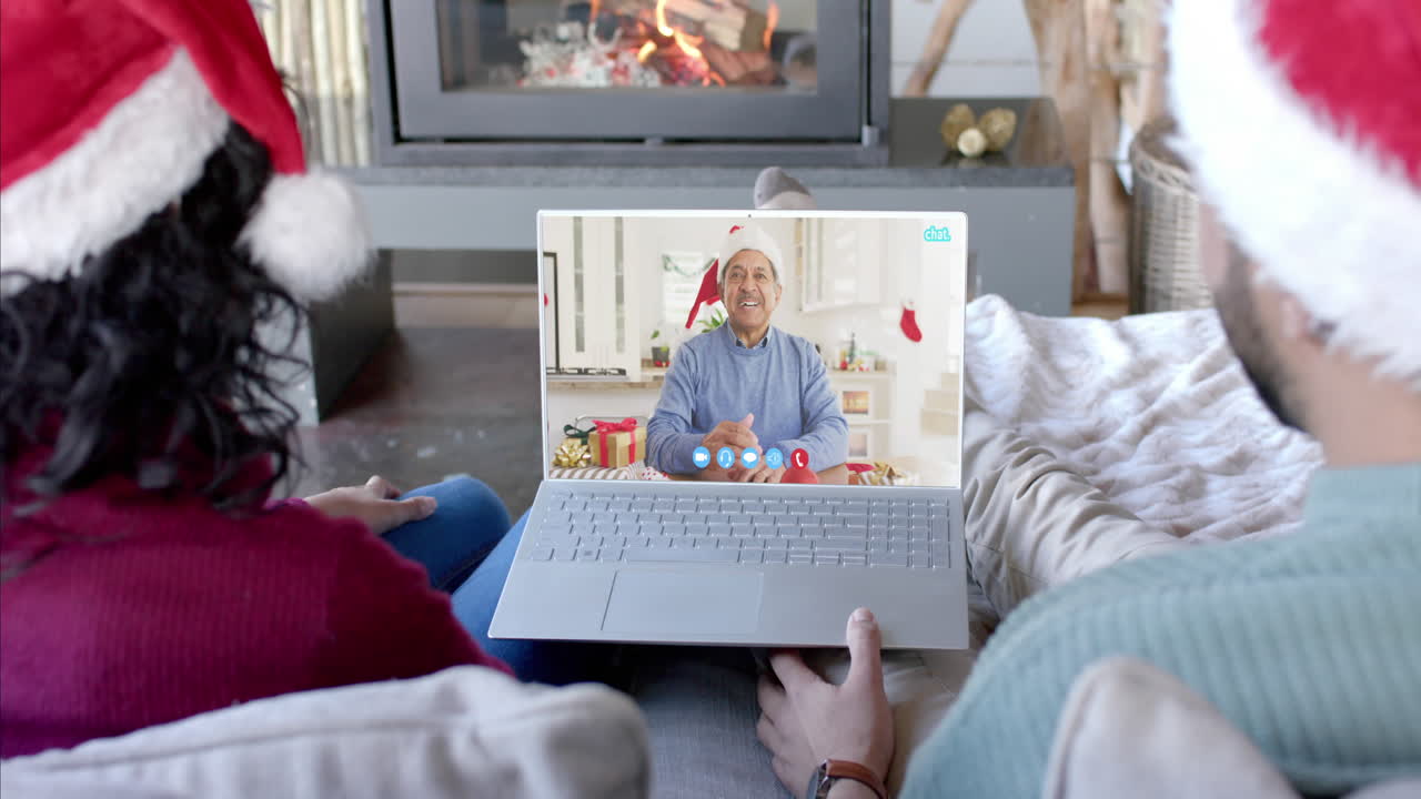 Coppia felice e diversificata e padre anziano in videochiamata di Natale via laptop, al rallentatore.
