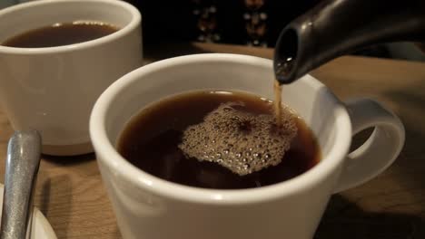 a steaming cup of english breakfast tea being poured into a white mug indoors