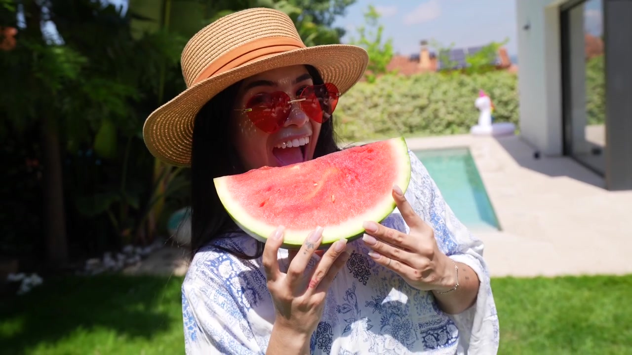 Donna felice che tiene in mano una fetta di anguria in un giardino soleggiato