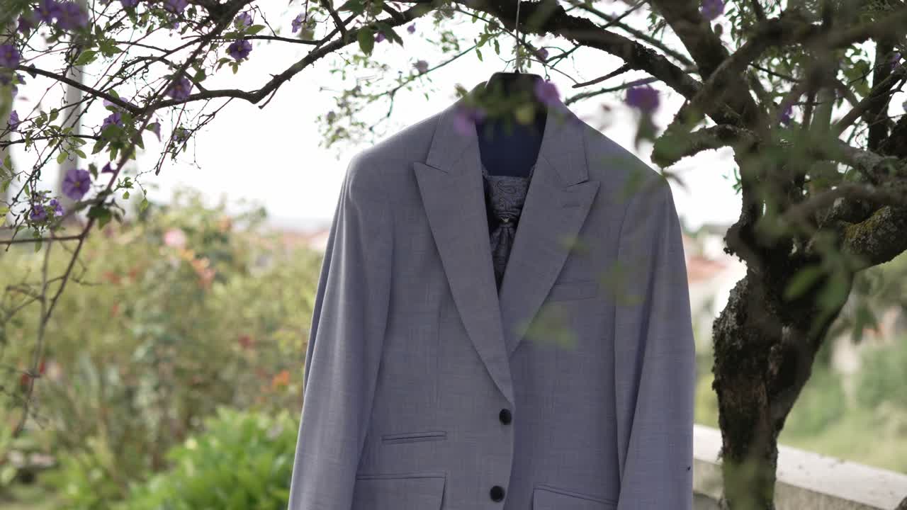 부드러운 자연 요소로 둘러싸인 정원에서 나무 가지에 끔하게 매달린 신랑의 슈트