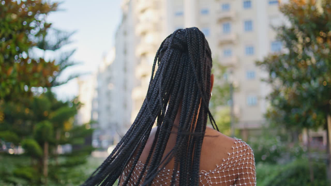 dreadlocks dama girando la cámara en el callejón retrato. chica de moda posando