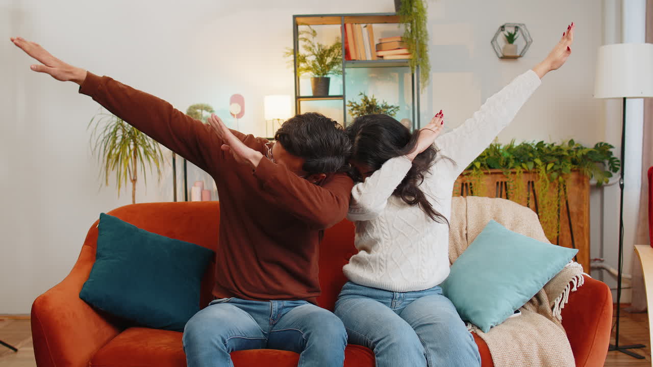 Excited indian couple dancing moving to rhythm dabbing raising hands making dub dance gesture