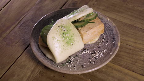 pan of a plate of steamed tofu bao buns on a handmade plate and wooden table