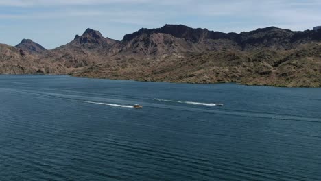 high-res 4k drone footage shows two fast boats racing full speed across lake havasu in the summer having fun with friends and family on a sunny day in the deserts of arizona-california