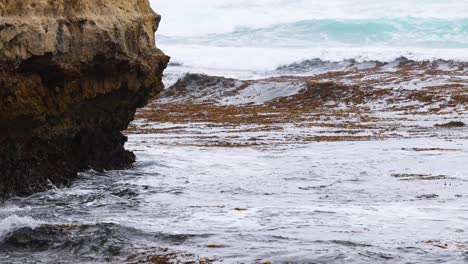 Dynamic ocean waves crash against rugged cliffs under overcast skies at Great Ocean Road, creating a dramatic coastal scene