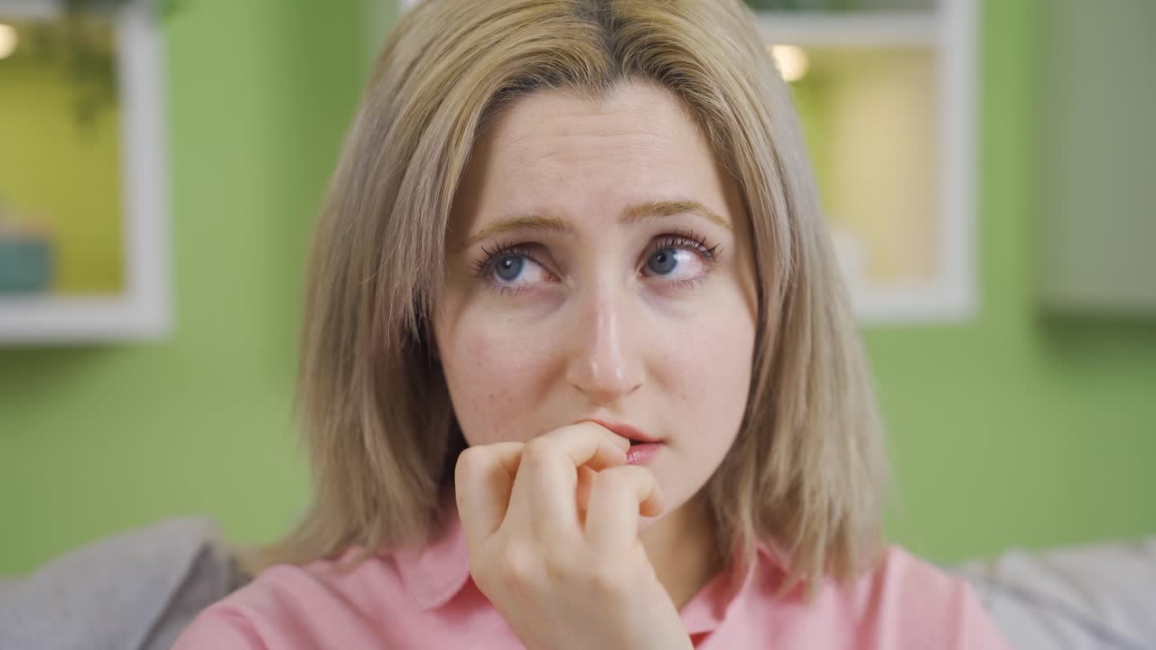 Donna a casa che si mangia le unghie per lo stress.