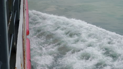 wake from ferry breaks calm water over side of railing narrow shot